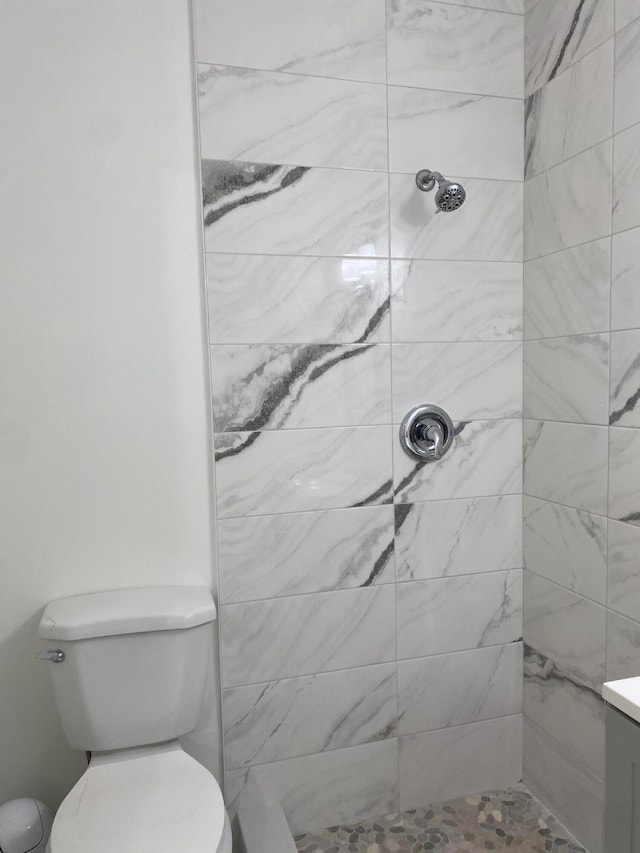 bathroom with tiled shower, vanity, and toilet