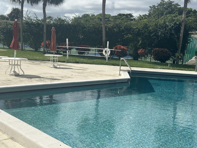 view of swimming pool featuring a lawn and a patio