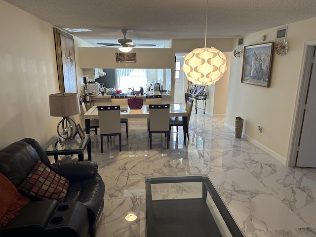 dining area featuring ceiling fan and a textured ceiling