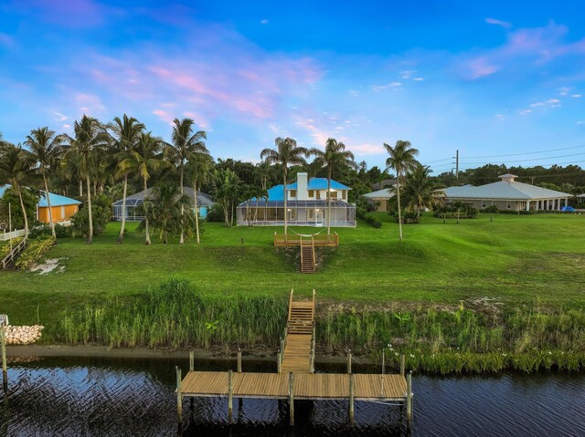 view of dock with a water view and a lawn