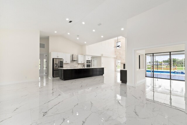 kitchen with wall chimney exhaust hood, stainless steel fridge, high vaulted ceiling, and a kitchen island