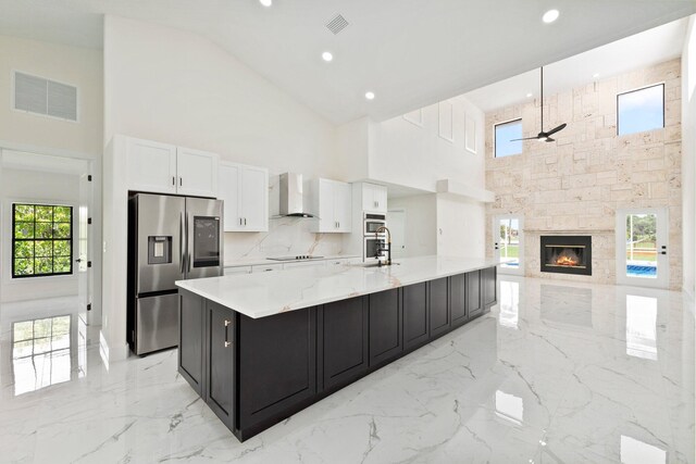 kitchen with high vaulted ceiling, appliances with stainless steel finishes, a fireplace, and ceiling fan