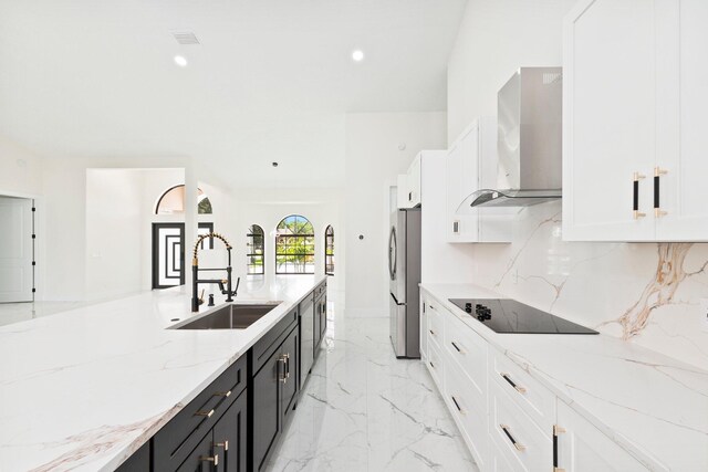 kitchen with sink, wall chimney range hood, stainless steel fridge, black electric stovetop, and tasteful backsplash