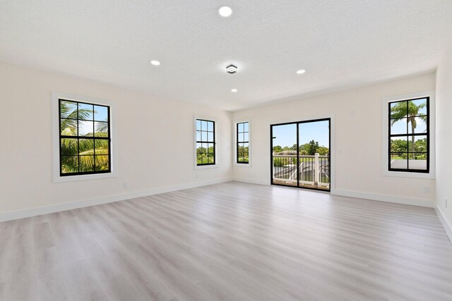 spare room featuring a textured ceiling and light hardwood / wood-style flooring