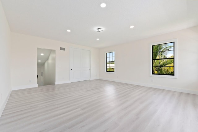 unfurnished room featuring light wood-type flooring, plenty of natural light, and a textured ceiling