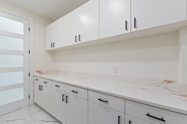 kitchen with light stone countertops and white cabinets