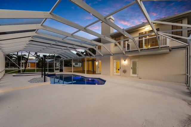 view of pool featuring glass enclosure, a hot tub, and a patio