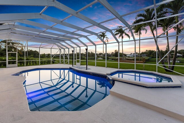 pool at dusk featuring a lawn, a lanai, and a patio