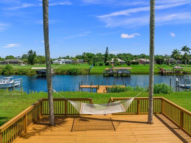 deck with a water view, a yard, and a dock