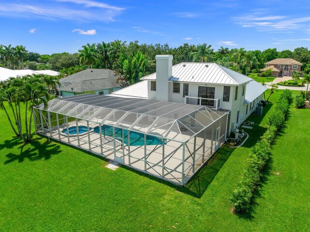 view of pool with central AC unit, glass enclosure, and a yard