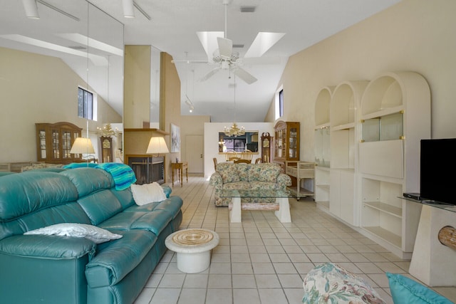 tiled living room with ceiling fan with notable chandelier, built in features, high vaulted ceiling, and a skylight