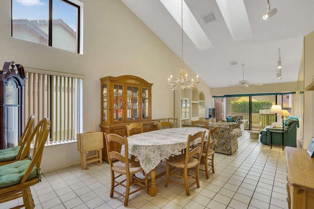 dining space with ceiling fan with notable chandelier, high vaulted ceiling, a skylight, and light tile patterned flooring