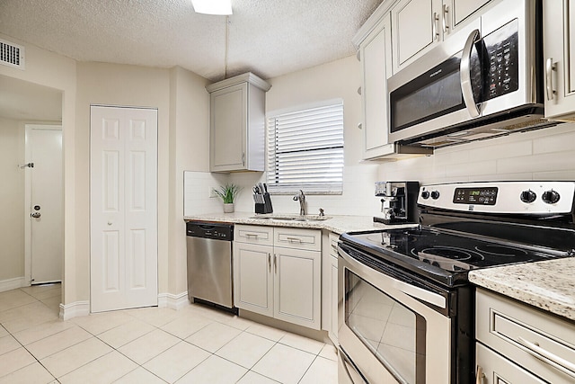 kitchen featuring tasteful backsplash, stainless steel appliances, a textured ceiling, and sink