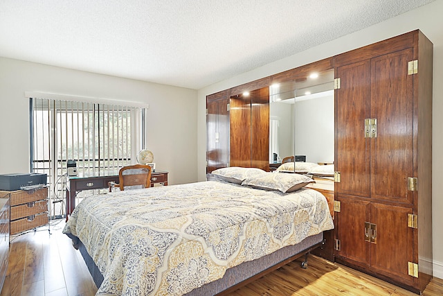 bedroom with a textured ceiling and light hardwood / wood-style flooring