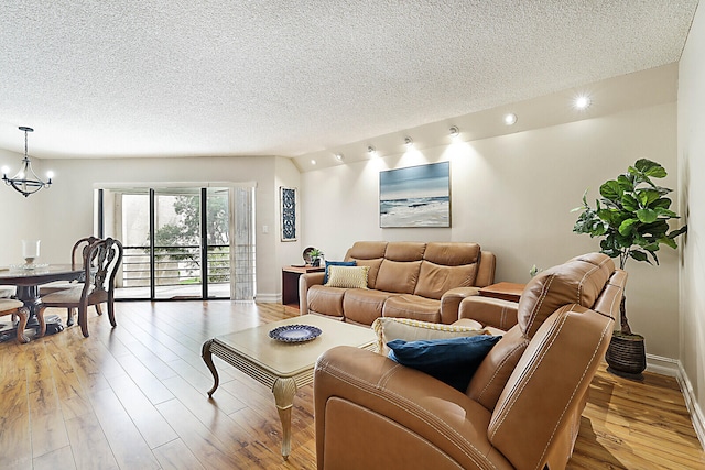 living room featuring a textured ceiling, light hardwood / wood-style flooring, and a notable chandelier