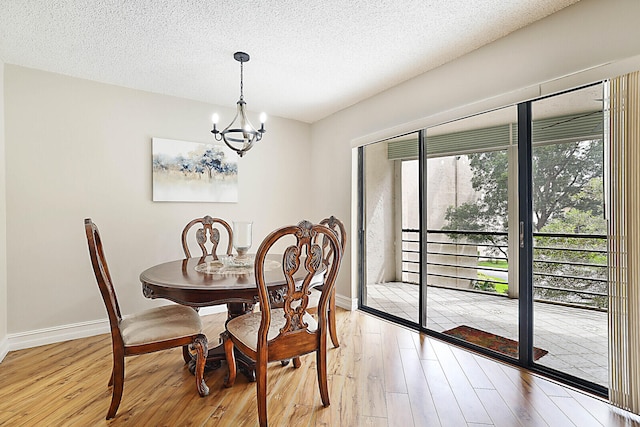 dining area with a textured ceiling, a chandelier, and light hardwood / wood-style floors