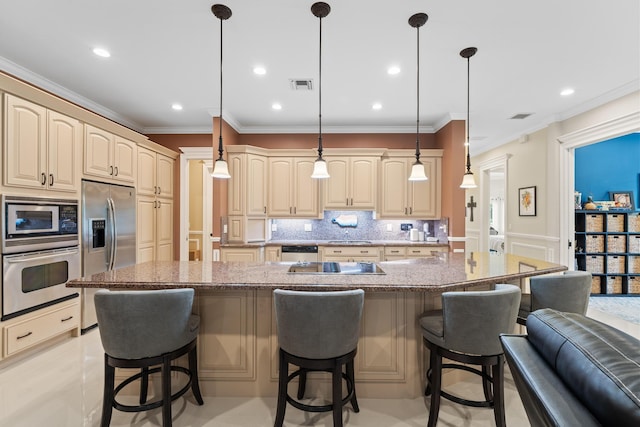 kitchen with light stone counters, a kitchen island with sink, appliances with stainless steel finishes, and hanging light fixtures