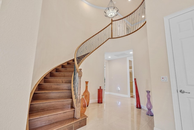 stairway featuring tile patterned floors, crown molding, and a towering ceiling