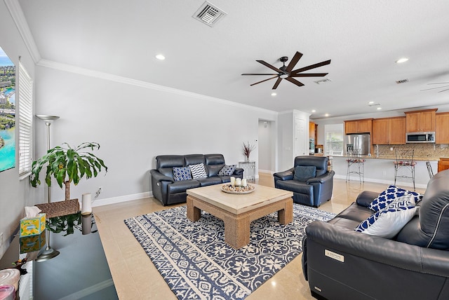 tiled living room with ornamental molding and ceiling fan