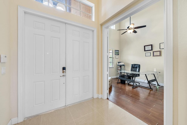 foyer with hardwood / wood-style flooring, ceiling fan, and a towering ceiling