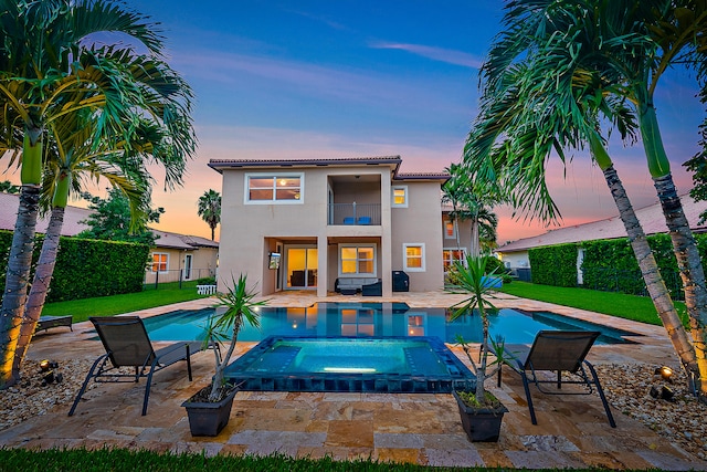 pool at dusk featuring a patio, a yard, and an in ground hot tub