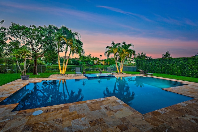 pool at dusk with a lawn and a patio