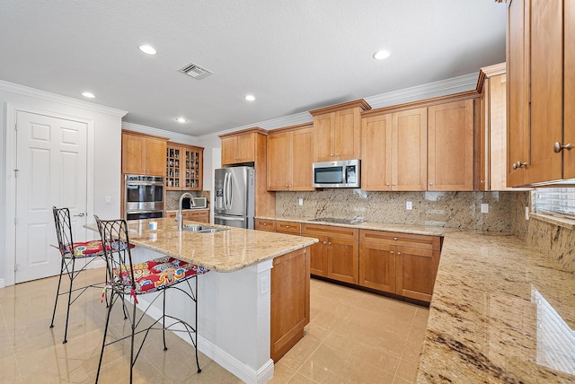 kitchen featuring appliances with stainless steel finishes, a kitchen bar, light stone countertops, sink, and a kitchen island with sink