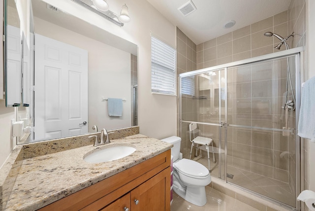 bathroom with toilet, vanity, and a shower with shower door