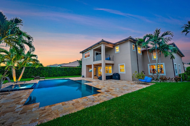 pool at dusk featuring a lawn, an in ground hot tub, and a patio area