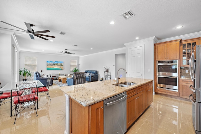 kitchen with light stone counters, a center island with sink, stainless steel appliances, a textured ceiling, and sink