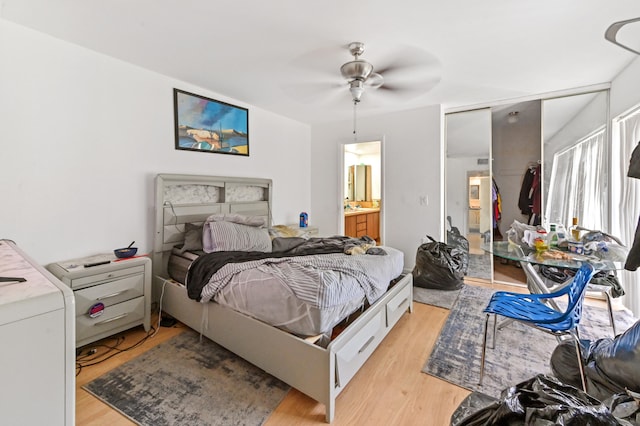 bedroom featuring connected bathroom, a closet, light hardwood / wood-style flooring, and ceiling fan