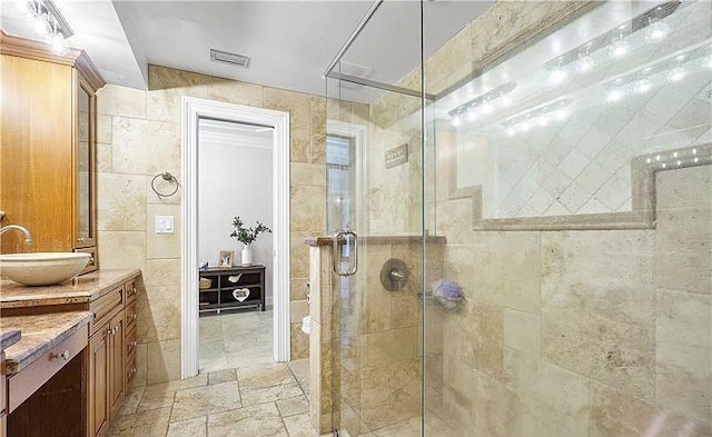 bathroom with vanity, tile walls, and a shower with shower door