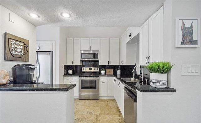 kitchen featuring appliances with stainless steel finishes, tasteful backsplash, kitchen peninsula, sink, and white cabinets