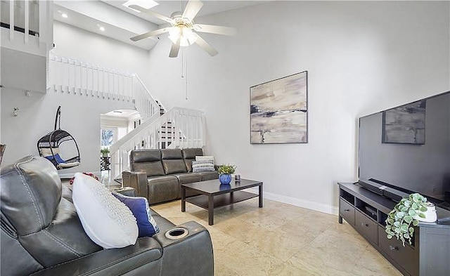 living room with ceiling fan and a towering ceiling