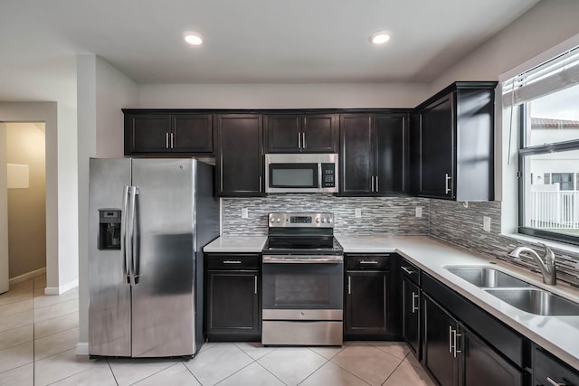 kitchen featuring appliances with stainless steel finishes, light tile patterned floors, decorative backsplash, and sink