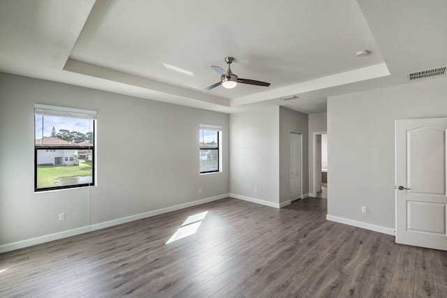 empty room featuring ceiling fan, a raised ceiling, and wood-type flooring