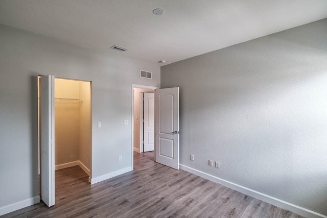 unfurnished bedroom with a closet, hardwood / wood-style floors, and a spacious closet