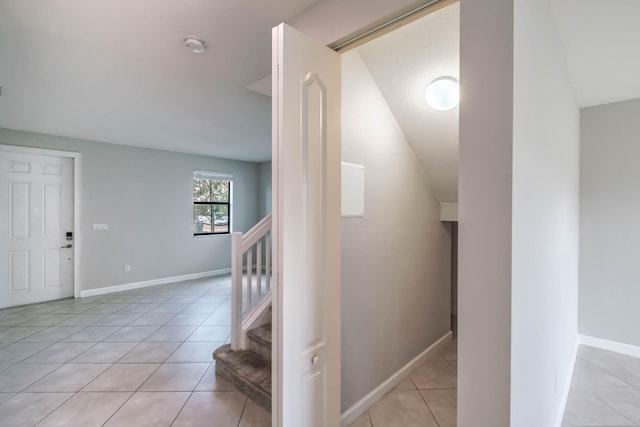 hallway featuring vaulted ceiling and light tile patterned floors