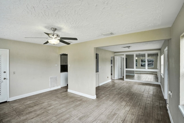 unfurnished room featuring ceiling fan, wood-type flooring, and a textured ceiling