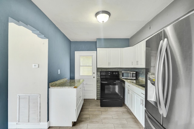 kitchen with dark stone counters, decorative backsplash, white cabinetry, and stainless steel appliances