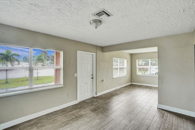 empty room featuring wood-type flooring and a textured ceiling