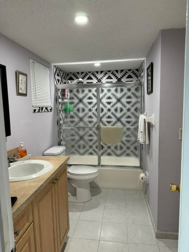 full bathroom featuring shower / bath combination with glass door, vanity, toilet, and a textured ceiling