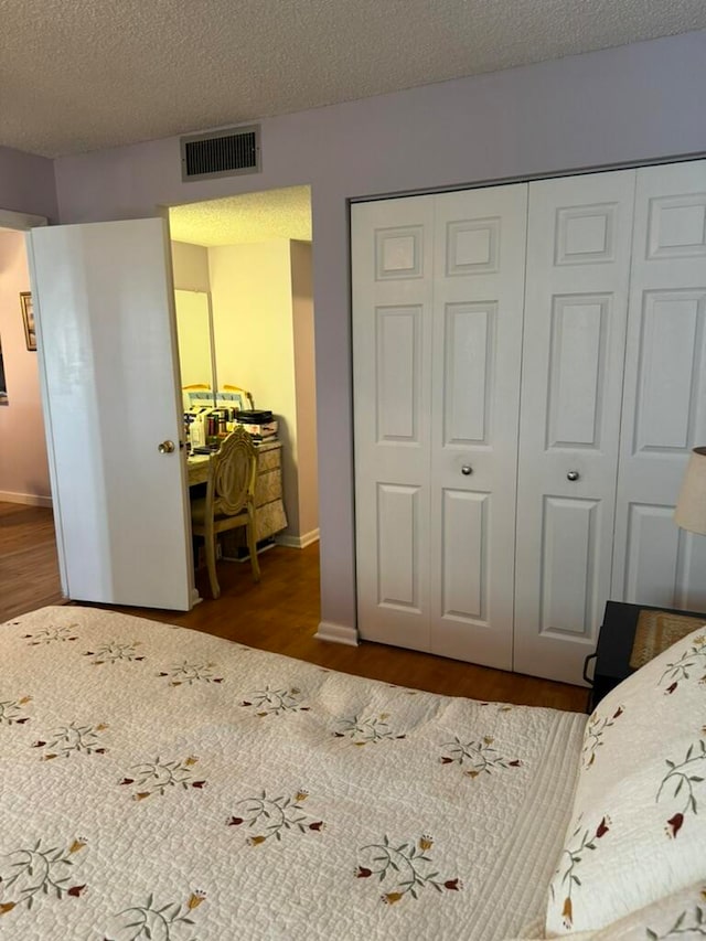 bedroom with a closet, hardwood / wood-style floors, and a textured ceiling