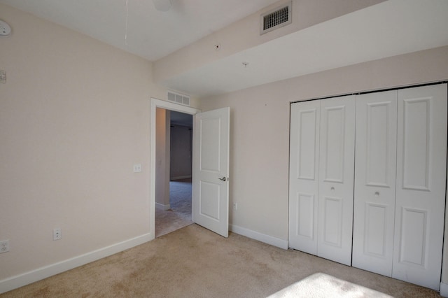 unfurnished bedroom with a closet, light colored carpet, and ceiling fan