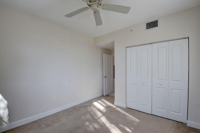 unfurnished bedroom with light colored carpet, ceiling fan, and a closet