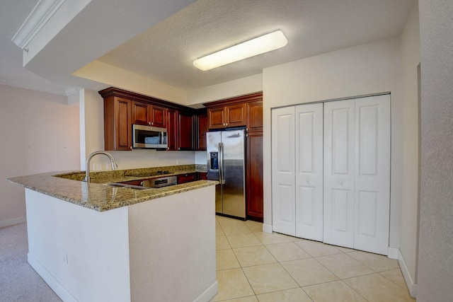 kitchen with light tile patterned floors, appliances with stainless steel finishes, kitchen peninsula, sink, and light stone counters