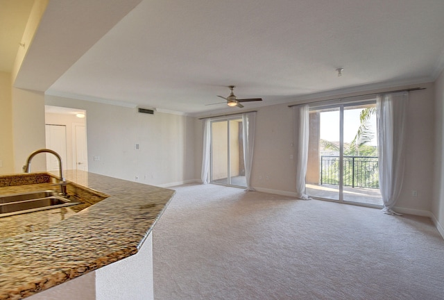 carpeted living room with ceiling fan, ornamental molding, and sink