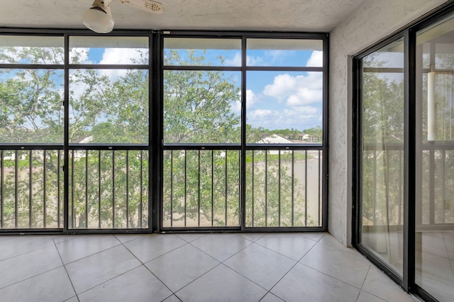 unfurnished sunroom featuring ceiling fan and plenty of natural light