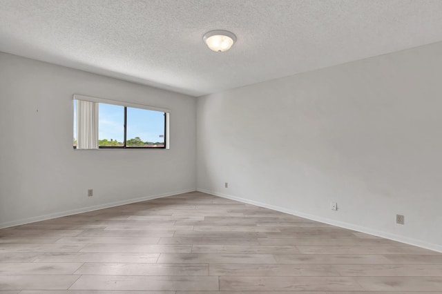 empty room with light hardwood / wood-style floors and a textured ceiling