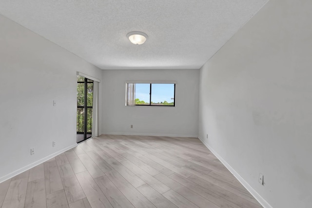 spare room with a textured ceiling and light hardwood / wood-style flooring